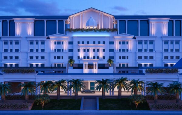 Luxury hotel exterior featuring white classical architecture with illuminated columns and palm trees at twilight