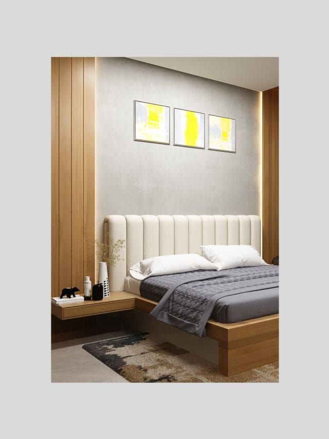 A modern bedroom with a light wood platform bed featuring a cream-colored channel-tufted headboard. White pillows and a grey textured throw blanket are on the bed. A light wood floating nightstand with a black bear figurine and various white and black objects is attached to a wooden paneled wall section. Three framed abstract paintings with yellow accents hang on the light grey wall above the headboard.